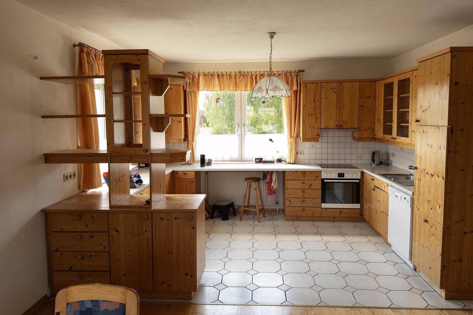 Traditionelle Holzküche mit gefliestem Boden, viel Stauraum und Fensterblick.