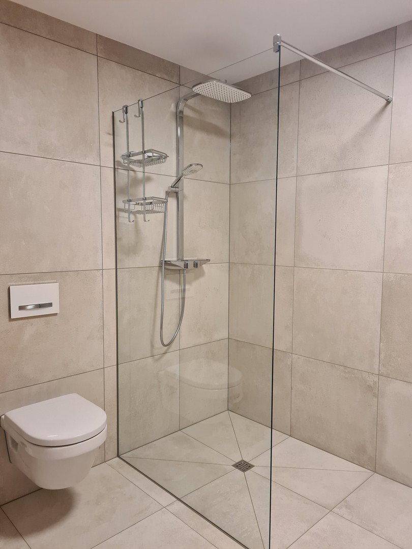 Modernes Badezimmer mit ebenerdiger Dusche, Wand-WC und hellen Fliesen.