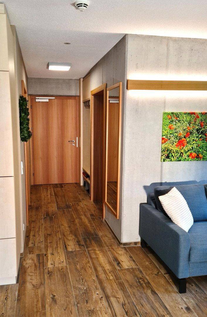 Flur mit Holzboden, Garderobe und Spiegel, der zum offenen Wohnbereich führt.