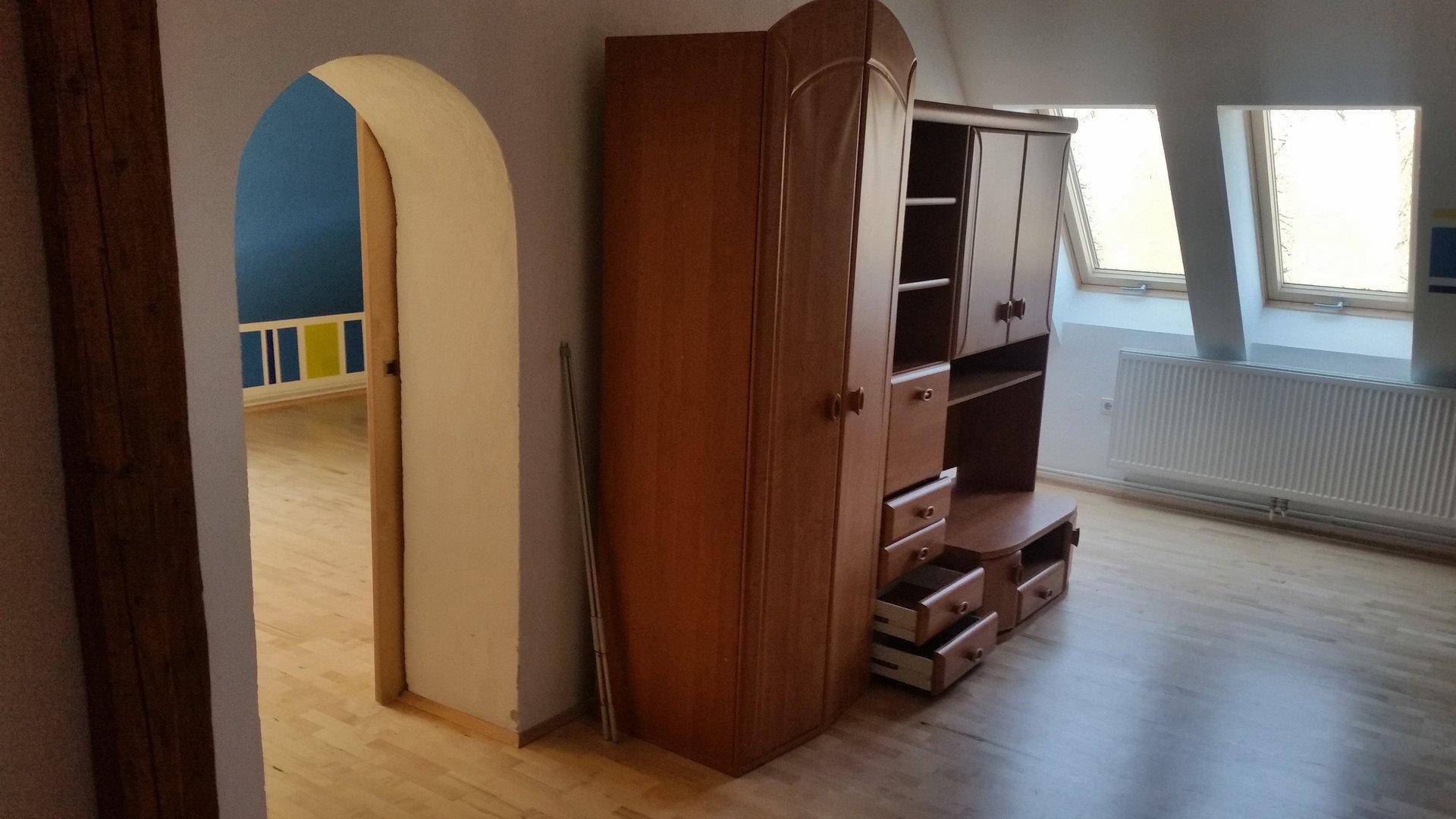 Dachgeschosszimmer mit Holzboden, Dachfenstern und einem Durchgang zu einem weiteren Raum.