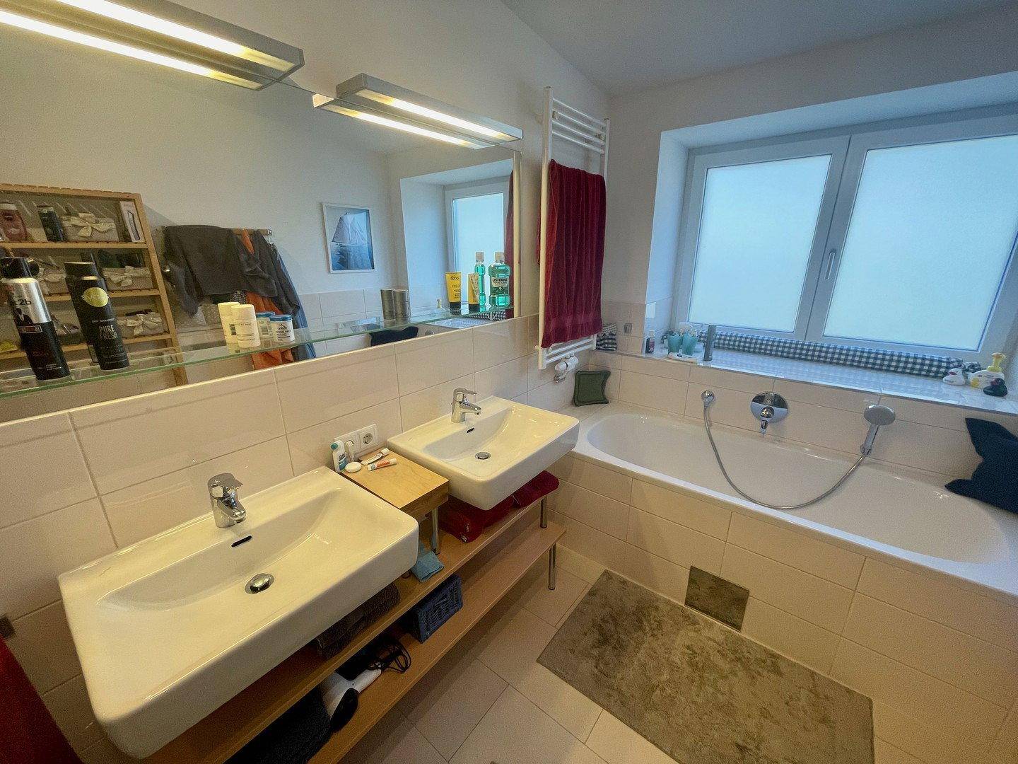 Helles Badezimmer mit zwei Waschbecken, Badewanne und großem Spiegel.