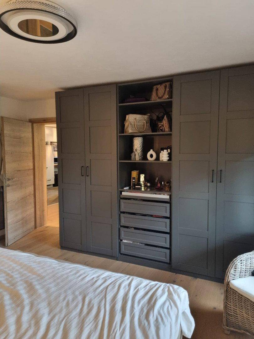 Schlafzimmer mit großem Kleiderschrank in Grau, Holzboden und Blick auf den Flur.
