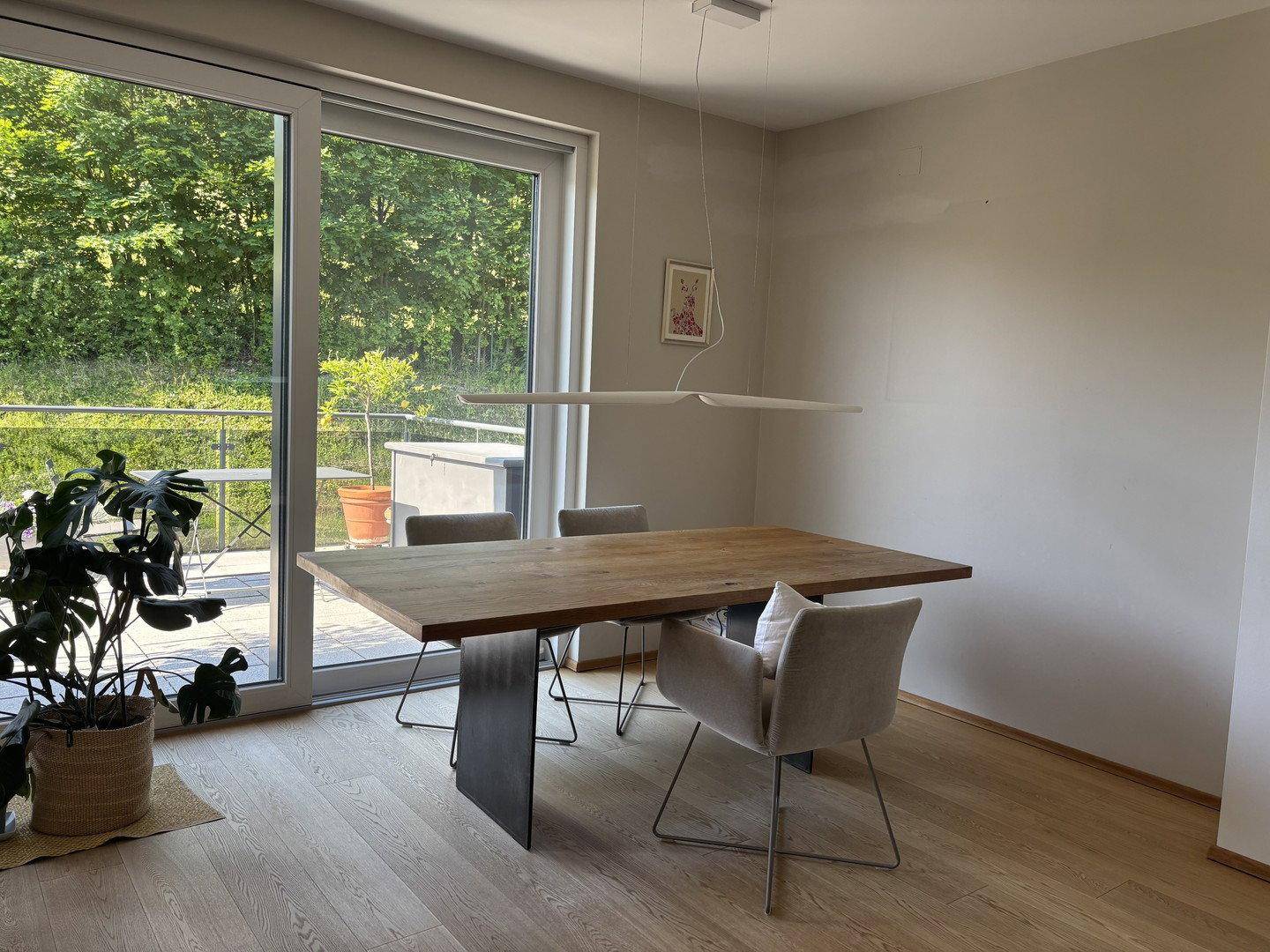 Heller Essbereich mit großem Holztisch, modernen Stühlen und Zugang zur Terrasse.