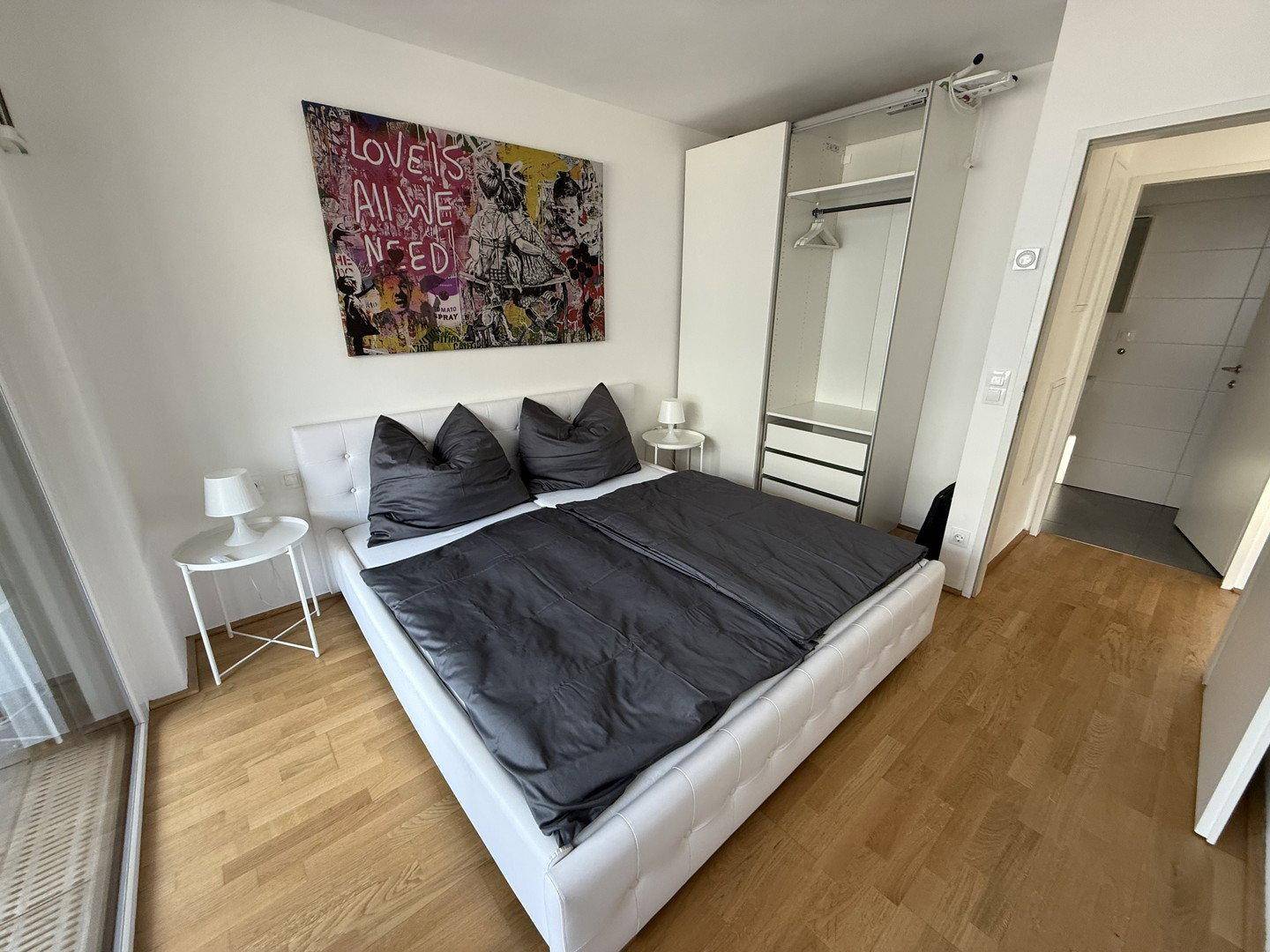Gemütliches Schlafzimmer mit Doppelbett, weißem Kleiderschrank und moderner Wanddekoration.