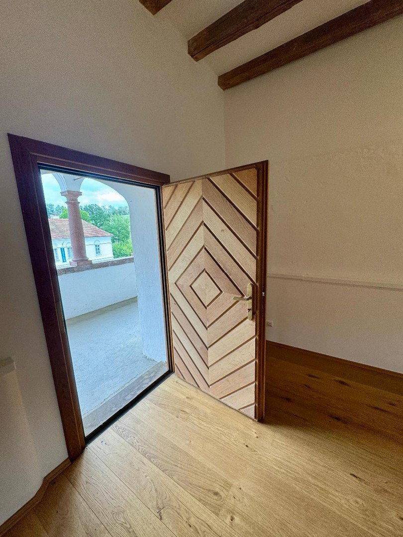 Heller Raum mit Holzboden und einer Tür, die zu einem Außenbereich führt.