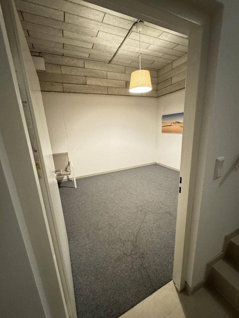 Kellerraum mit grauem Teppichboden und einer Decke aus Betonblöcken, ideal als Abstellraum.