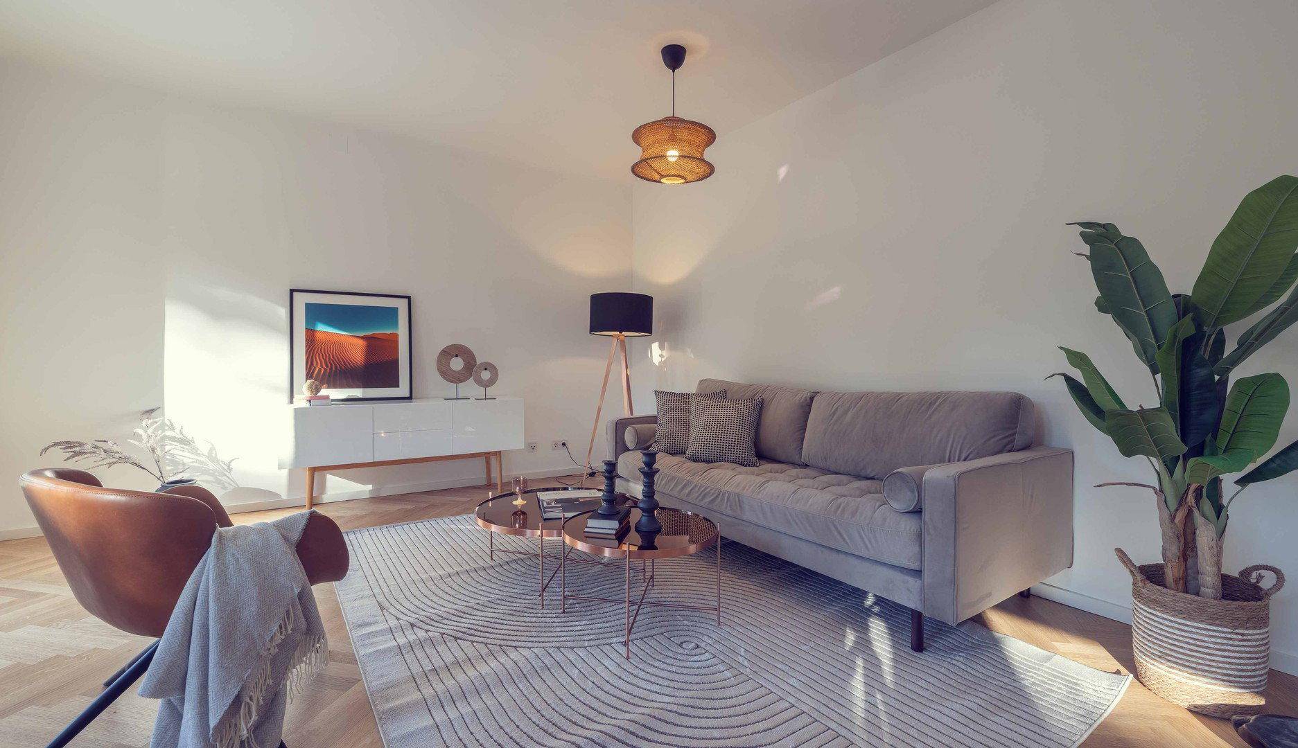 Geräumiges Wohnzimmer mit bequemer Couch, stilvollen Möbeln und viel natürlichem Licht.