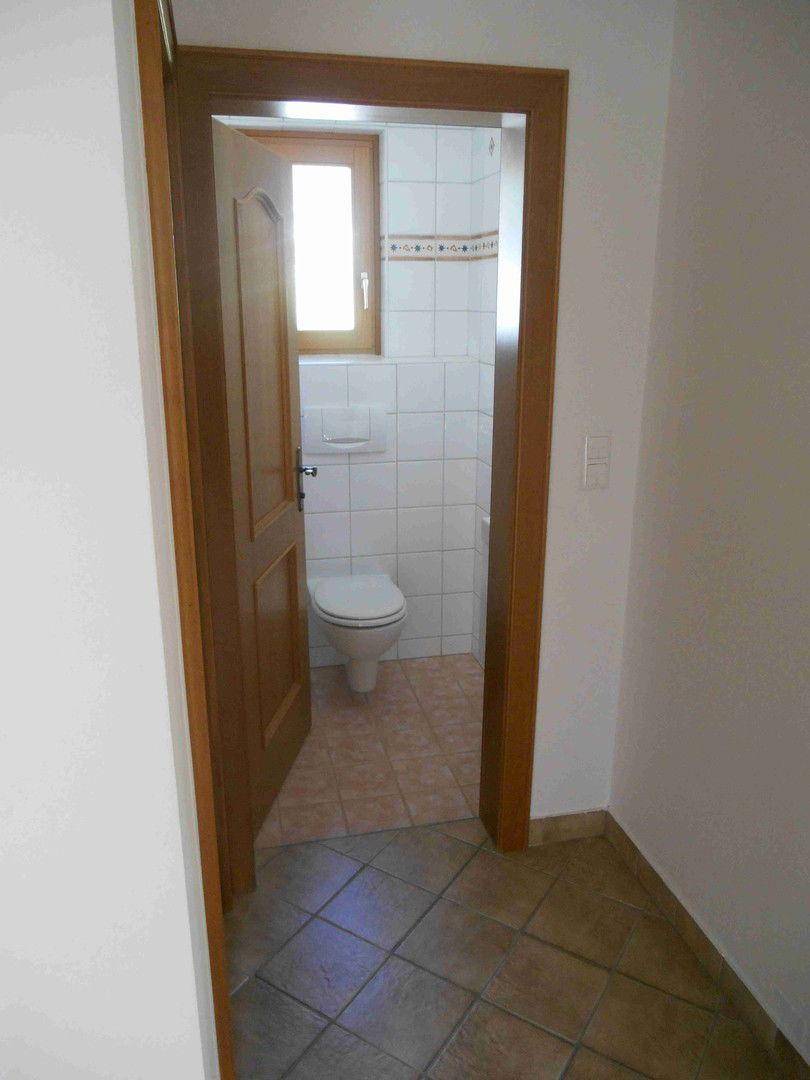 Kleines Gäste-WC mit Fenster, wandhängendem WC und hellen Fliesen.