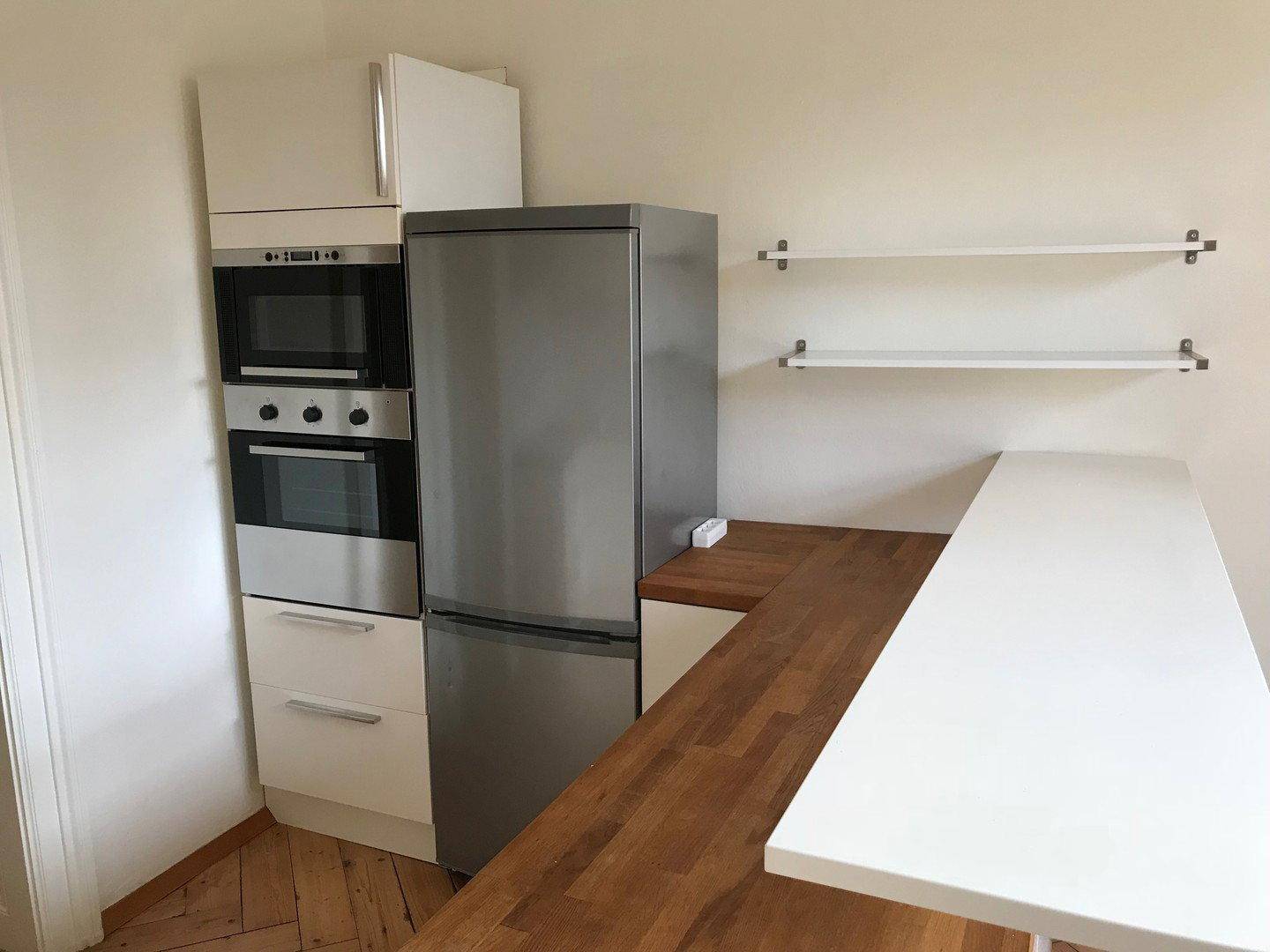 Funktionale Küche mit integriertem Backofen, Mikrowelle, Kühlschrank und einer praktischen Arbeitsfläche.
