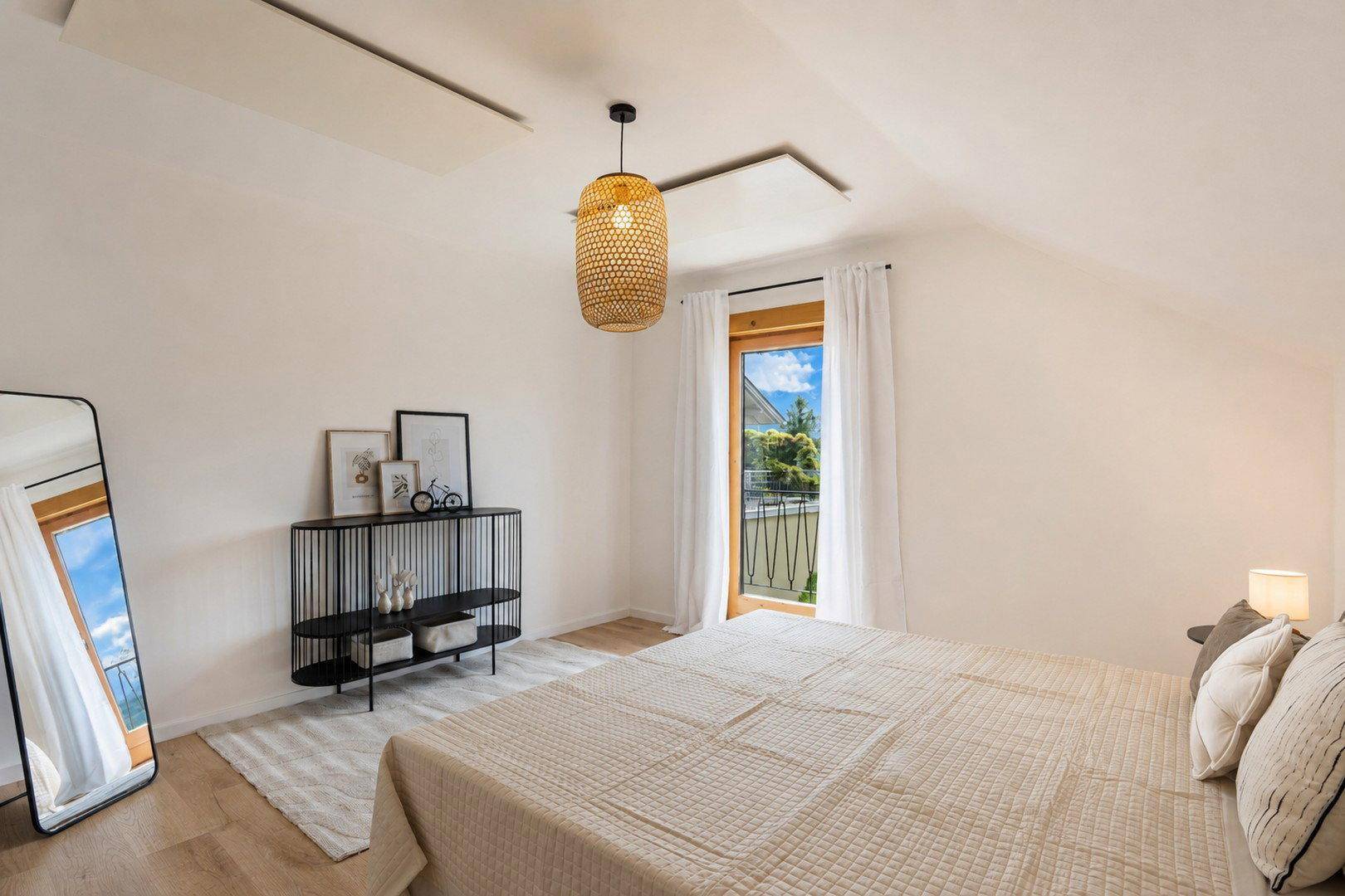 Schlafzimmer mit Doppelbett, moderner Einrichtung und Zugang zu einem französischen Balkon.