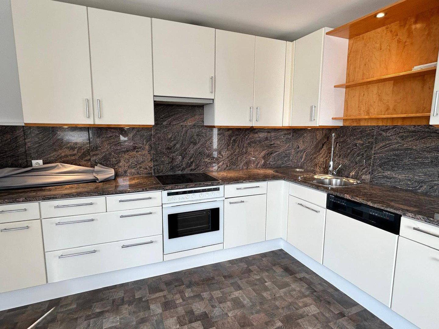 Moderne Einbauküche mit cremefarbenen Fronten, dunkler Granitarbeitsplatte und Spülbecken.