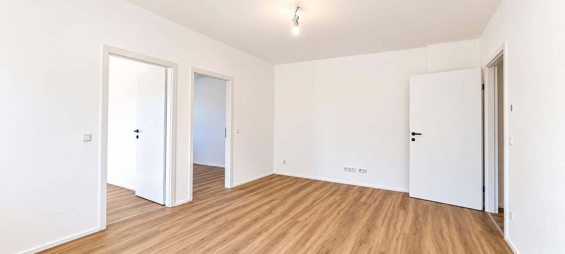 Helles Zimmer mit Laminatboden und mehreren Türen, das eine flexible Raumaufteilung ermöglicht.