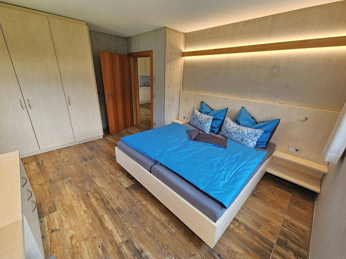 Schlafzimmer mit Doppelbett, Holzboden und Einbauschränken in hellem, modernem Design.