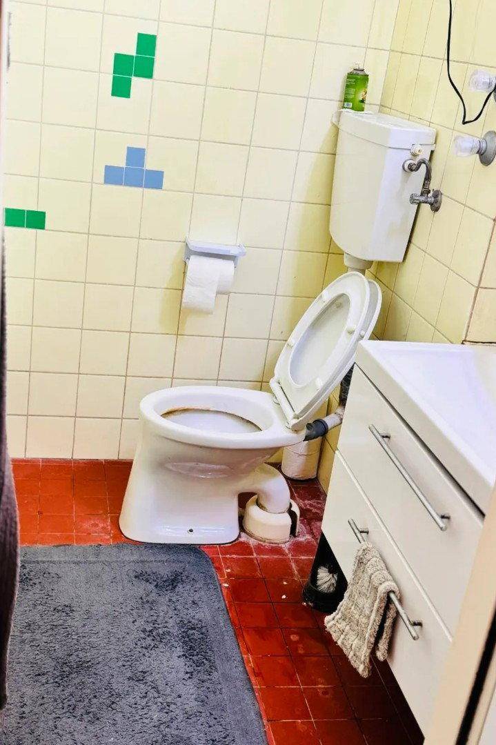 Separate Toilette mit WC, Waschbeckenunterschrank und farbigen Wandfliesen.