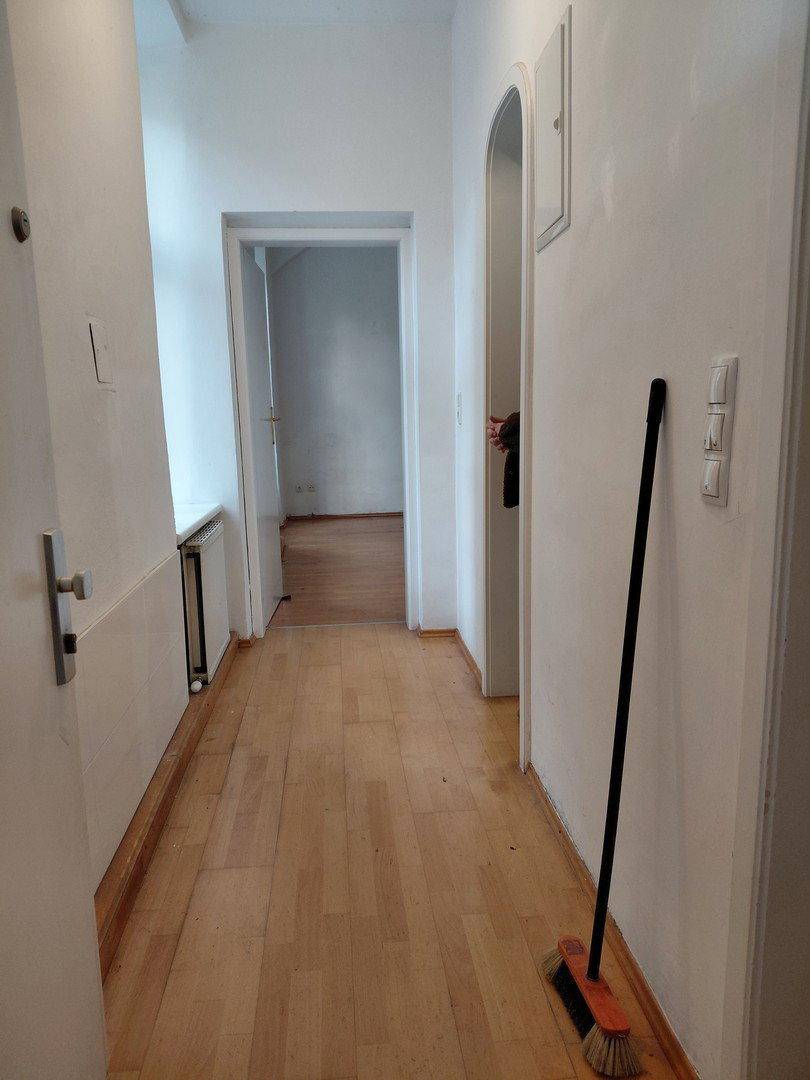 Heller Flur mit Holzparkettboden und weißen Wänden, der zu weiteren Räumen führt.