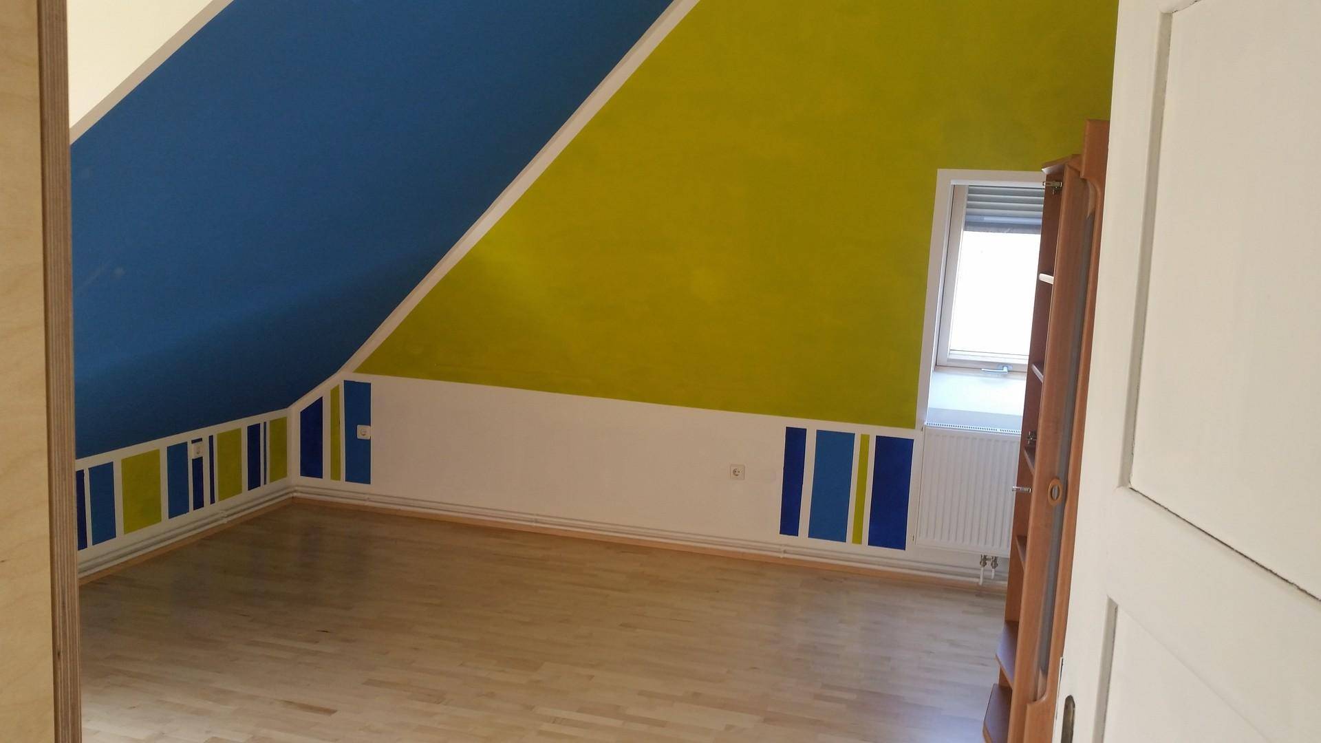 Helles Dachgeschosszimmer mit schrägen Wänden, Holzboden und farbenfroher Gestaltung.