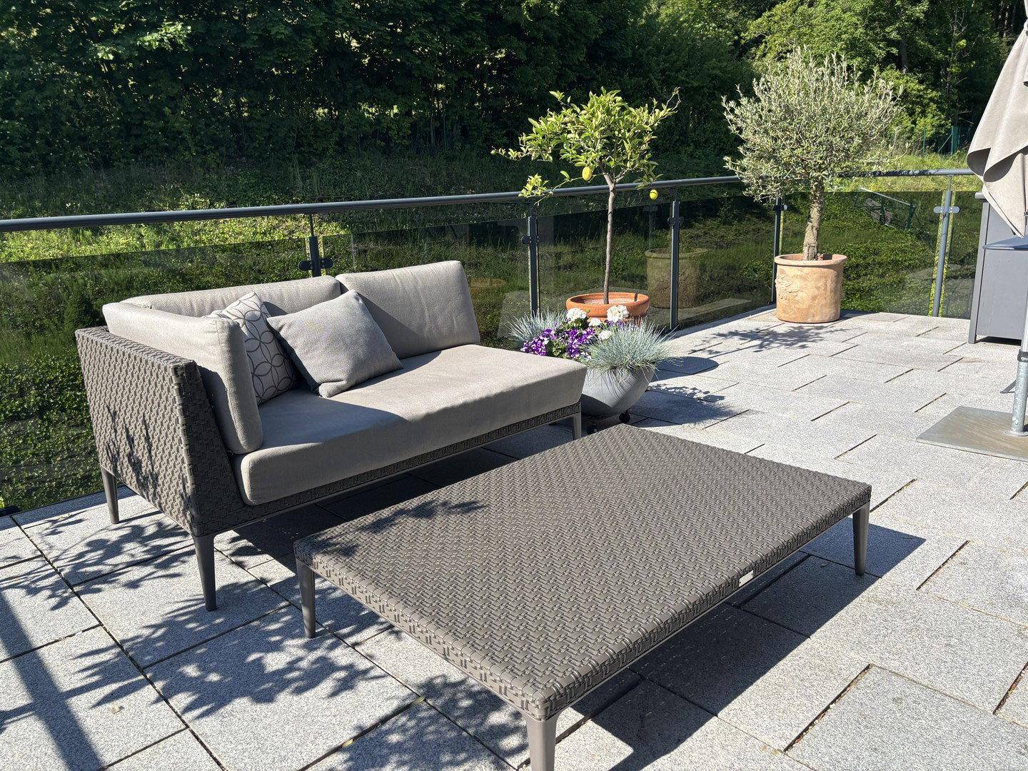Sonniger Terrassenbereich mit modernen Loungemöbeln und Topfpflanzen.