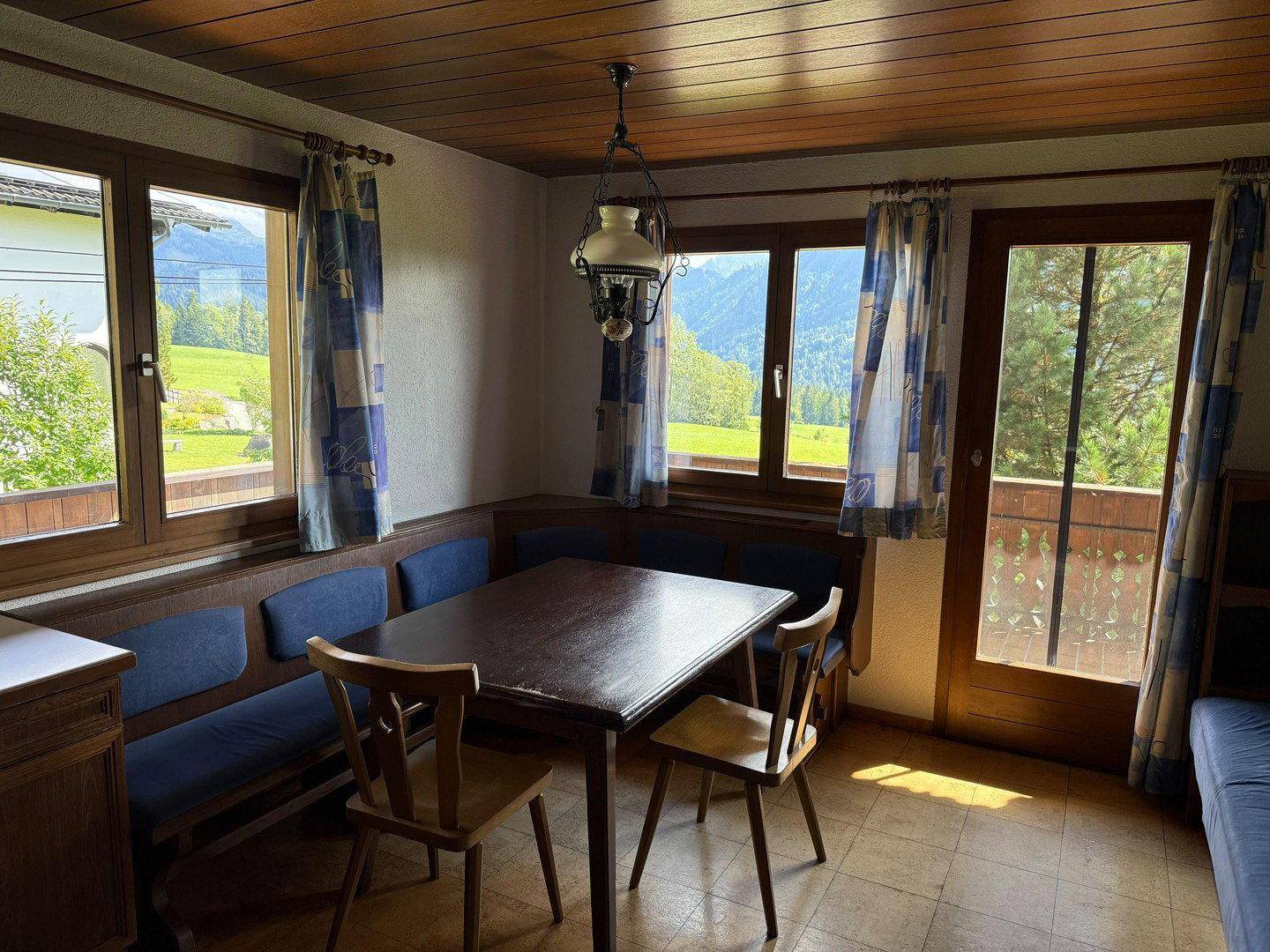 Gemütlicher Essbereich mit Holztisch, Eckbank und Fenstern mit Blick auf die Berge.