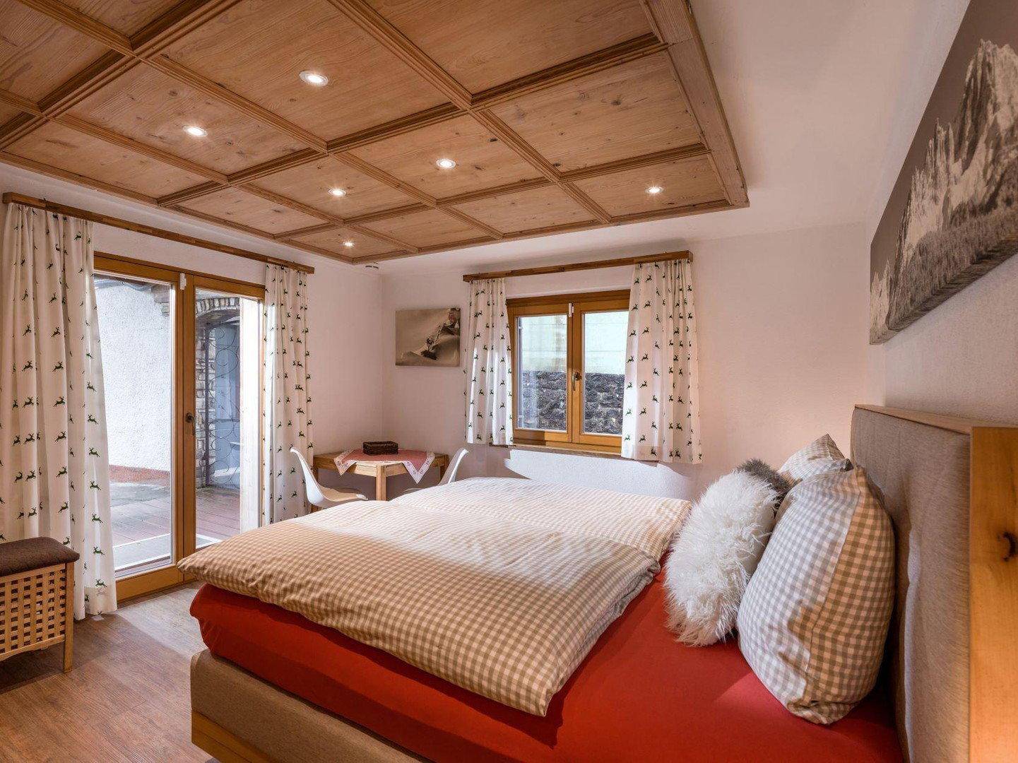 Helles Schlafzimmer mit Holzkassettendecke, Doppelbett und Zugang zur Terrasse.
