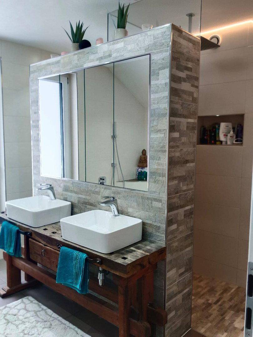 Modernes Badezimmer mit Doppelwaschbecken, Spiegel und Duschbereich mit Steinoptikfliesen.