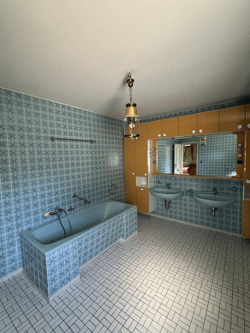 Geräumiges Badezimmer mit blauen Fliesen, Badewanne und Doppelwaschbecken.