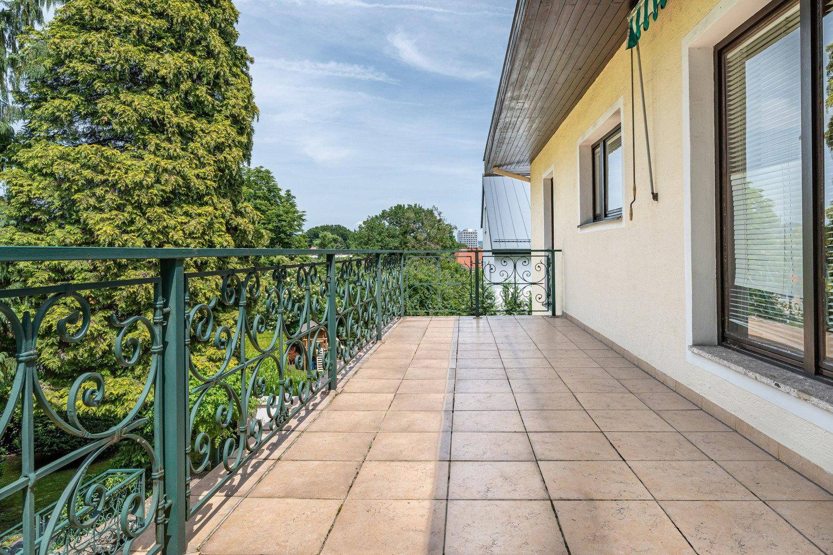 Langer Balkon mit schmiedeeisernem Geländer und Fliesenboden, bietet Weitblick.