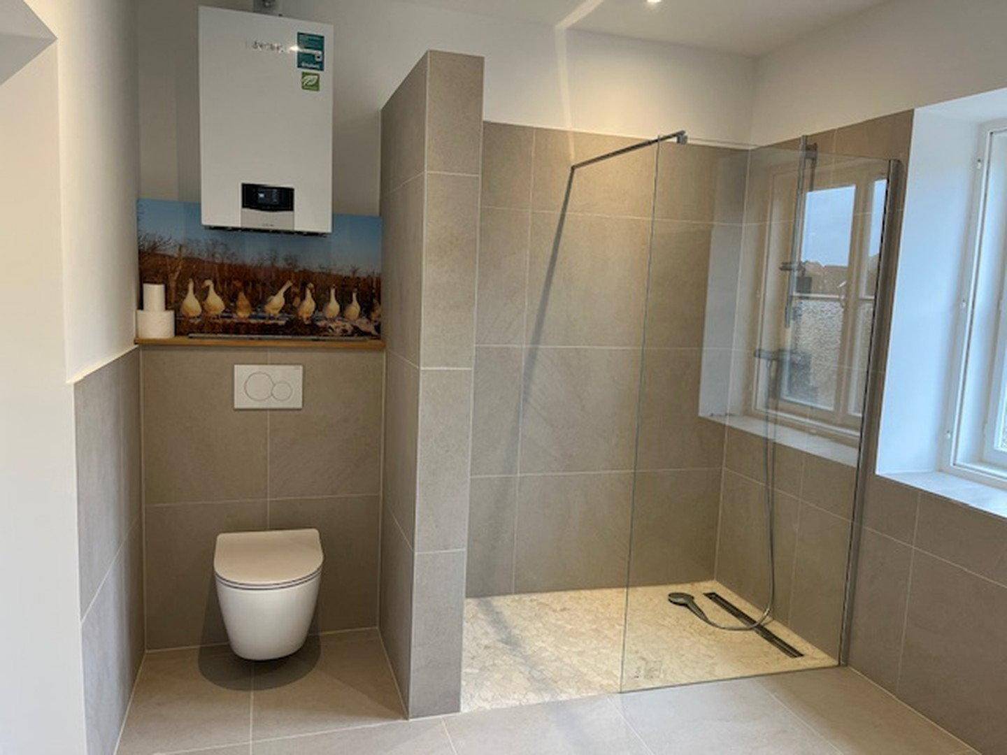 Modernes Badezimmer mit begehbarer Dusche, Wand-WC und beigefarbenen Fliesen.
