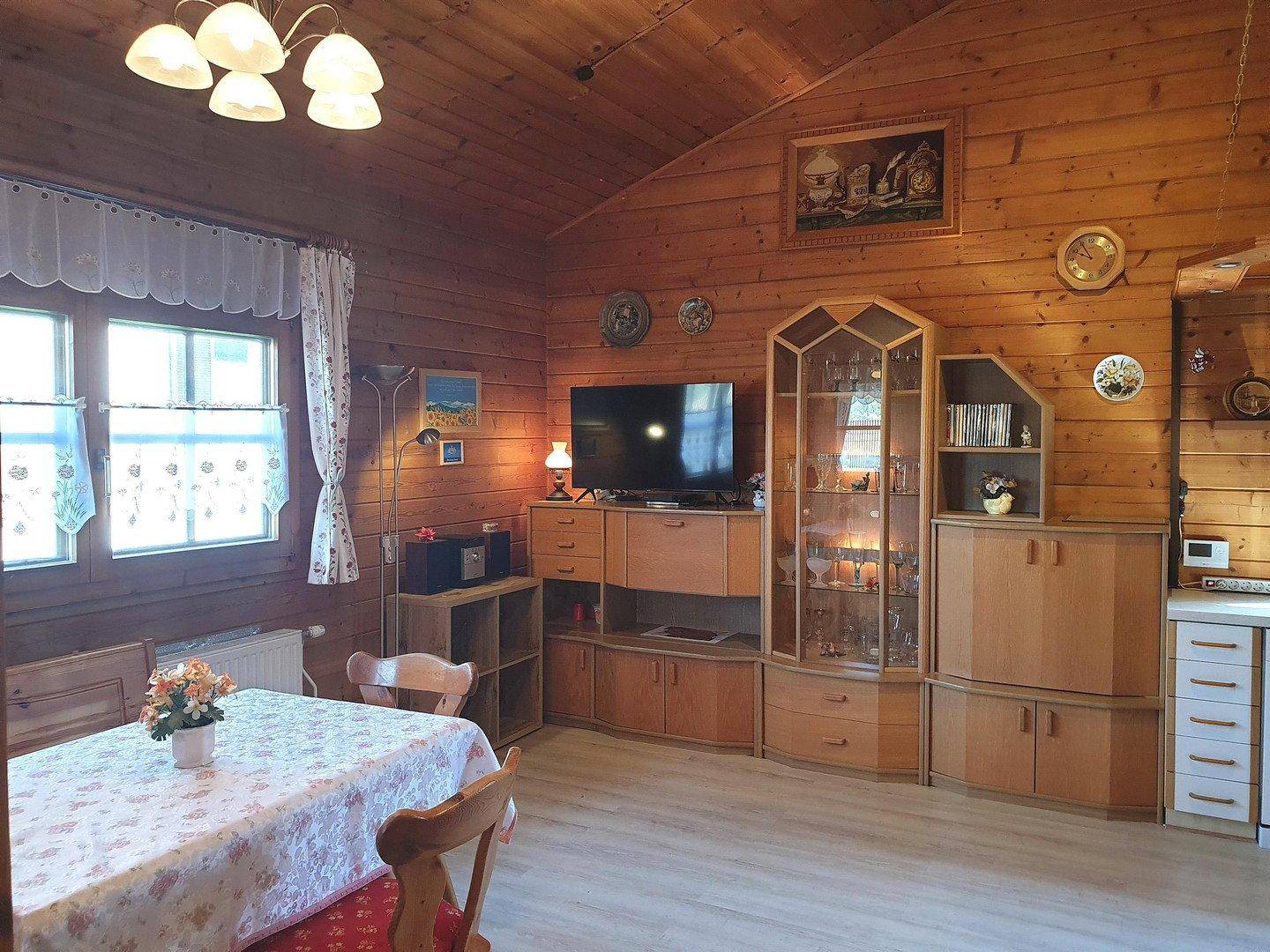 Geräumiger Wohnbereich mit Holzvertäfelung, TV-Möbel und dekorativen Elementen im Landhausstil.