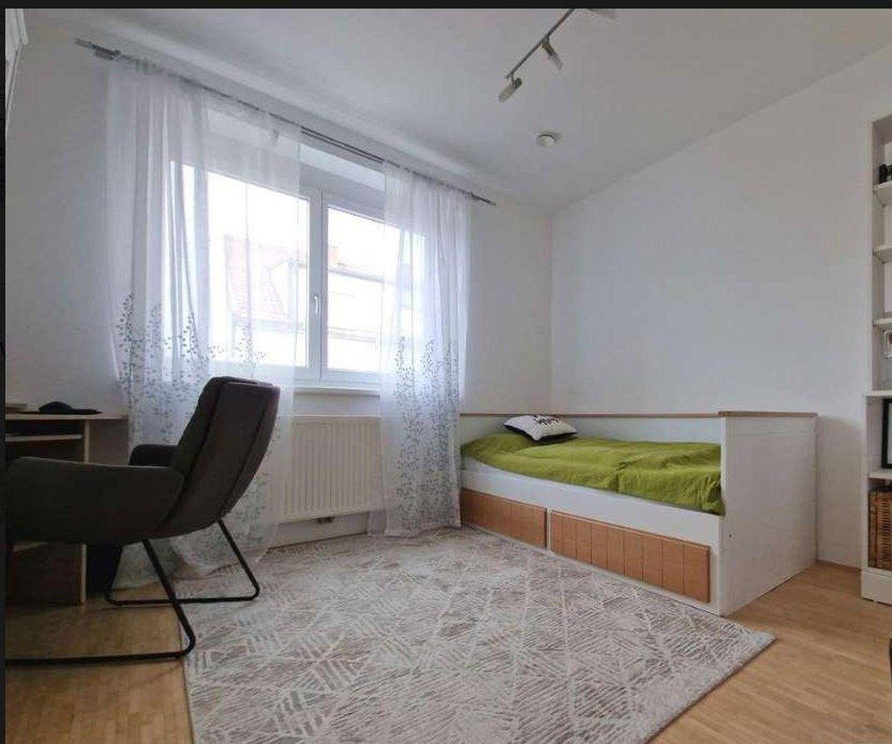 Gemütliches Schlafzimmer mit Einzelbett, Schreibtisch und hellem Parkettboden.