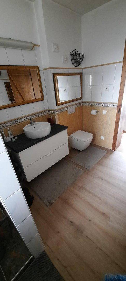 Helles Badezimmer mit Einzelwaschbecken, Toilette und einer Kombination aus Holz- und Fliesenoberflächen.