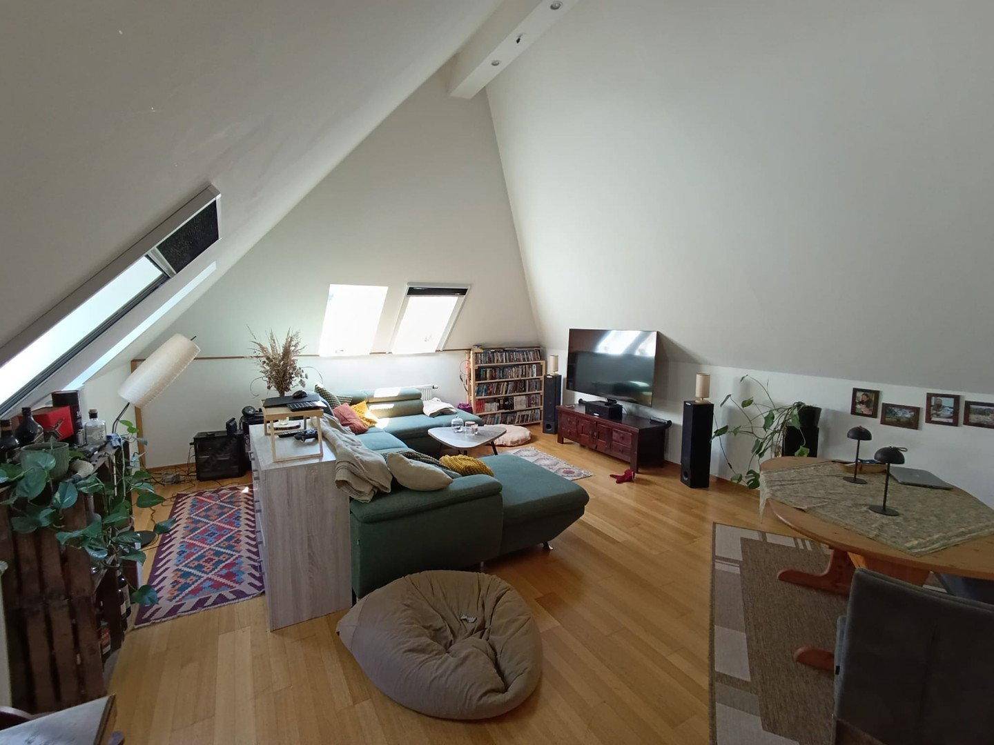 Helles Wohnzimmer im Dachgeschoss mit Holzboden, Dachfenstern und Unterhaltungselektronik.