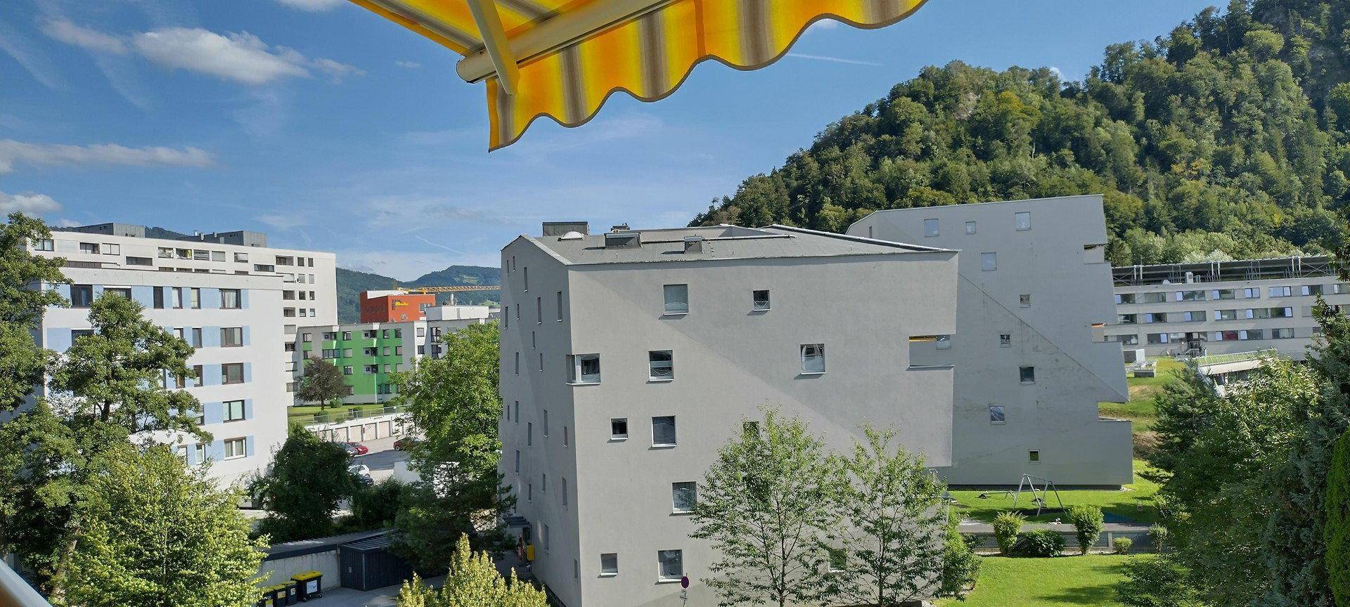 Außenansicht von Mehrfamilienhäusern mit viel Grün und Bäumen in der Umgebung.