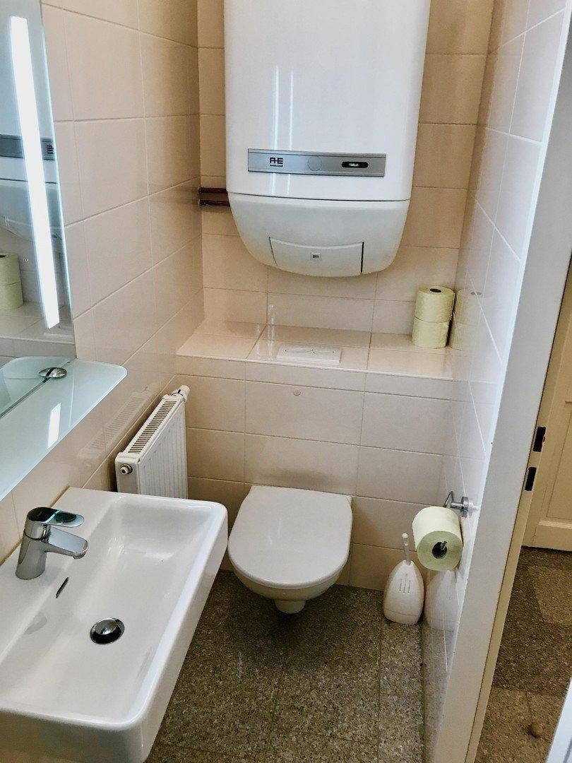 Kleines WC mit Toilette, Waschbecken und Wandheizkörper.