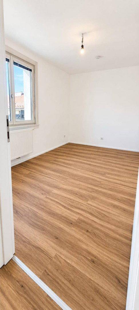 Helles Schlafzimmer mit Laminatboden und weiß gestrichenen Wänden, bietet eine ruhige Atmosphäre.