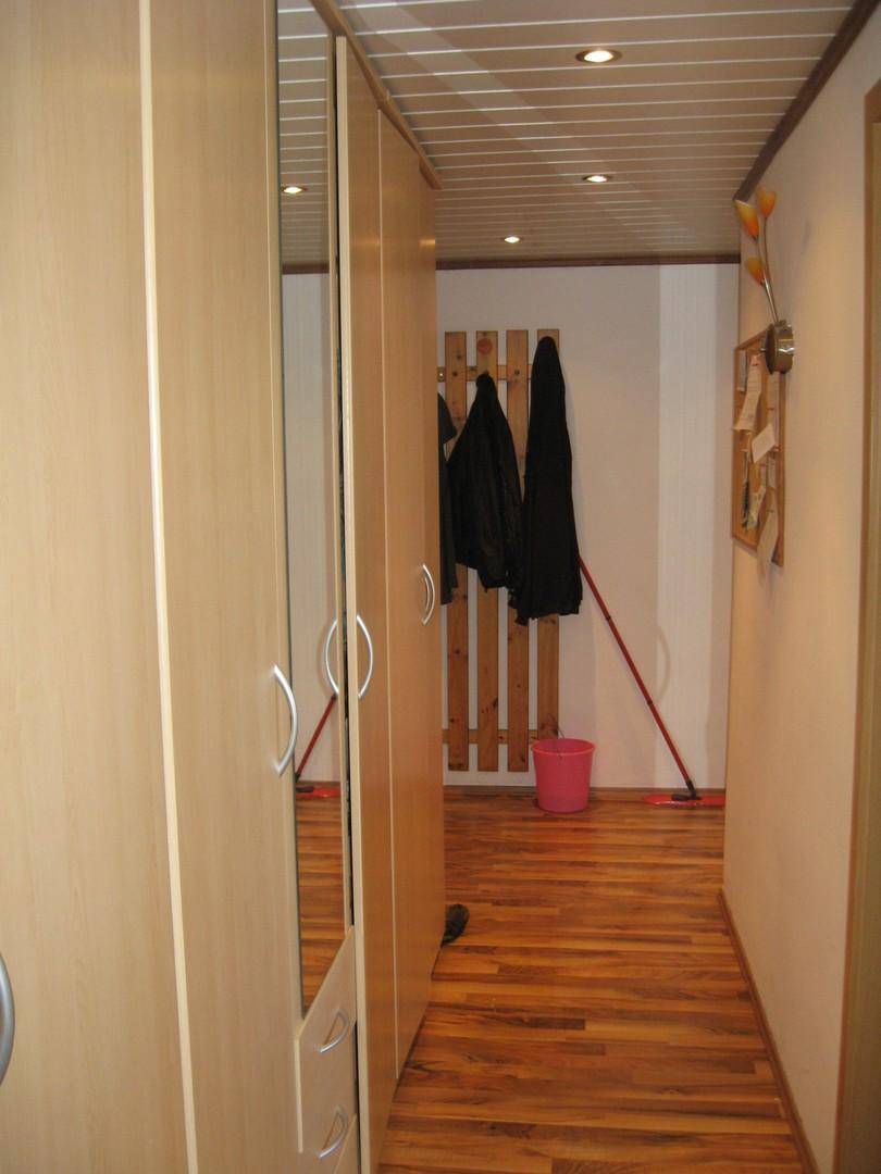 Heller Flur mit Holzfußboden, Einbauschränken und Garderobe, die viel Stauraum bietet.