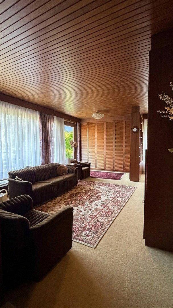 Geräumiges Wohnzimmer mit Holzdecke, bequemen Sofas und großem Fenster.