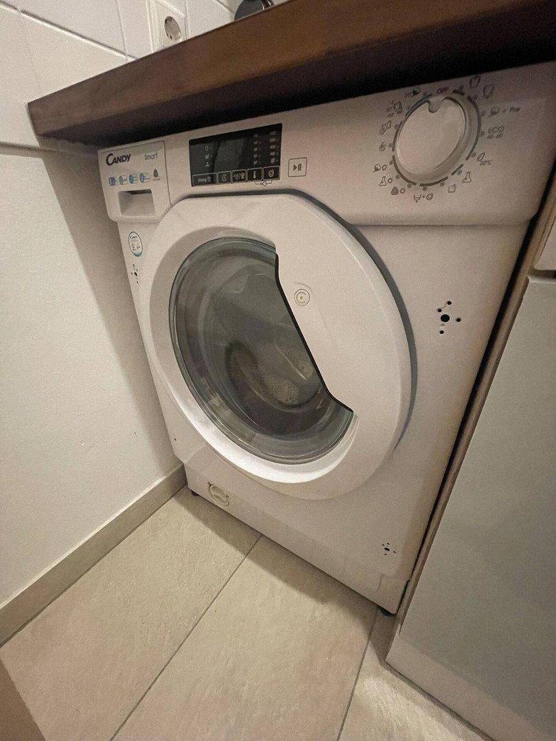 Waschmaschine unter einer Holzarbeitsplatte, integriert in eine Küchenzeile.