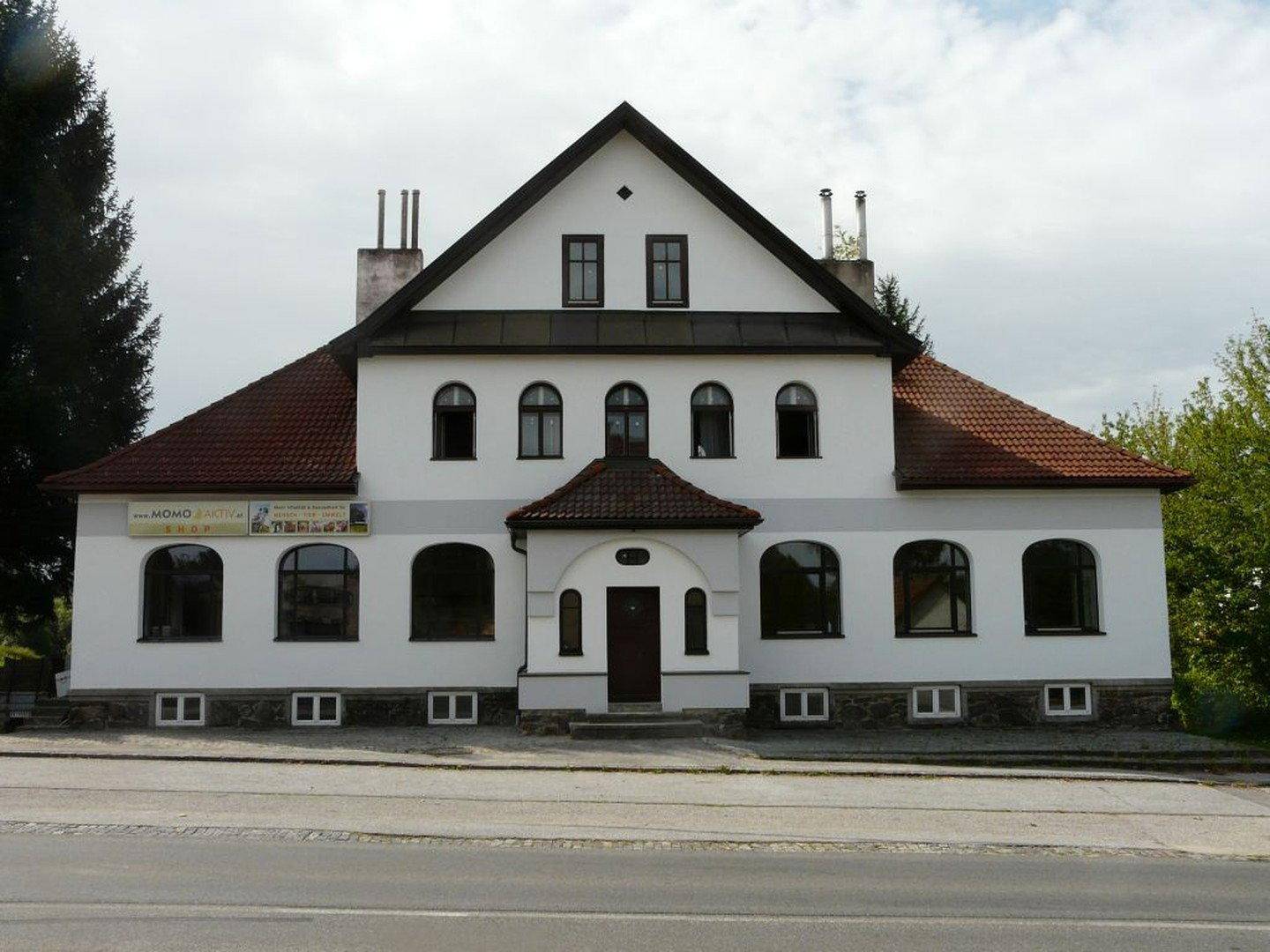 Vorderansicht des historischen Gebäudes mit markantem Eingangsbereich und großen Fenstern.