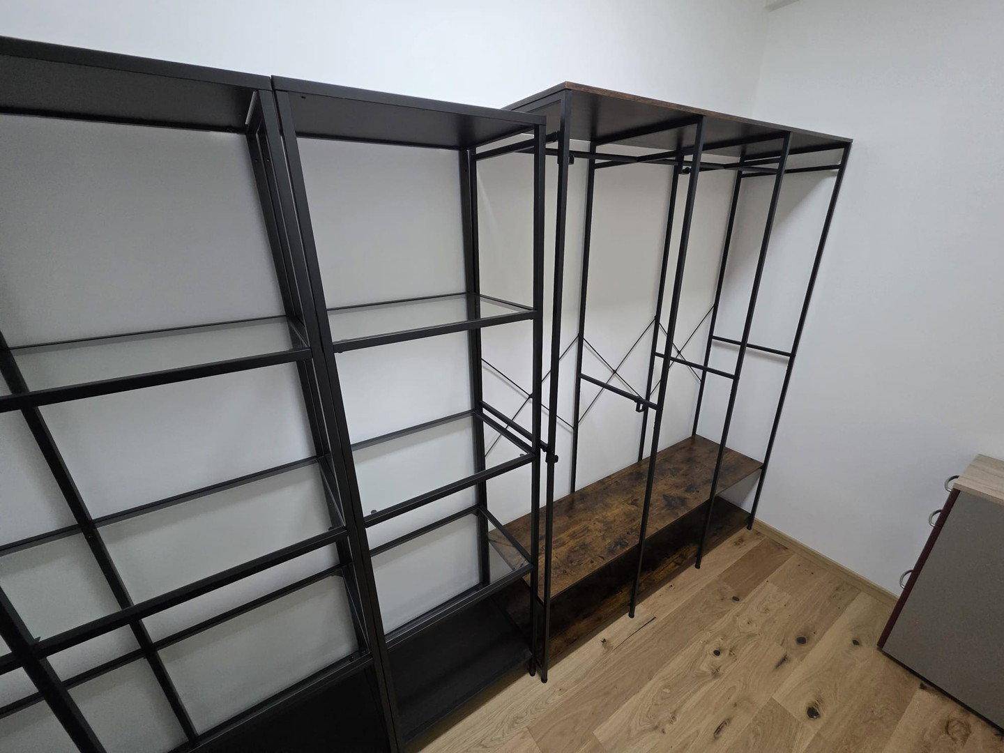 Detailansicht des begehbaren Kleiderschranks mit modernen Metallregalen und Holzoptik.