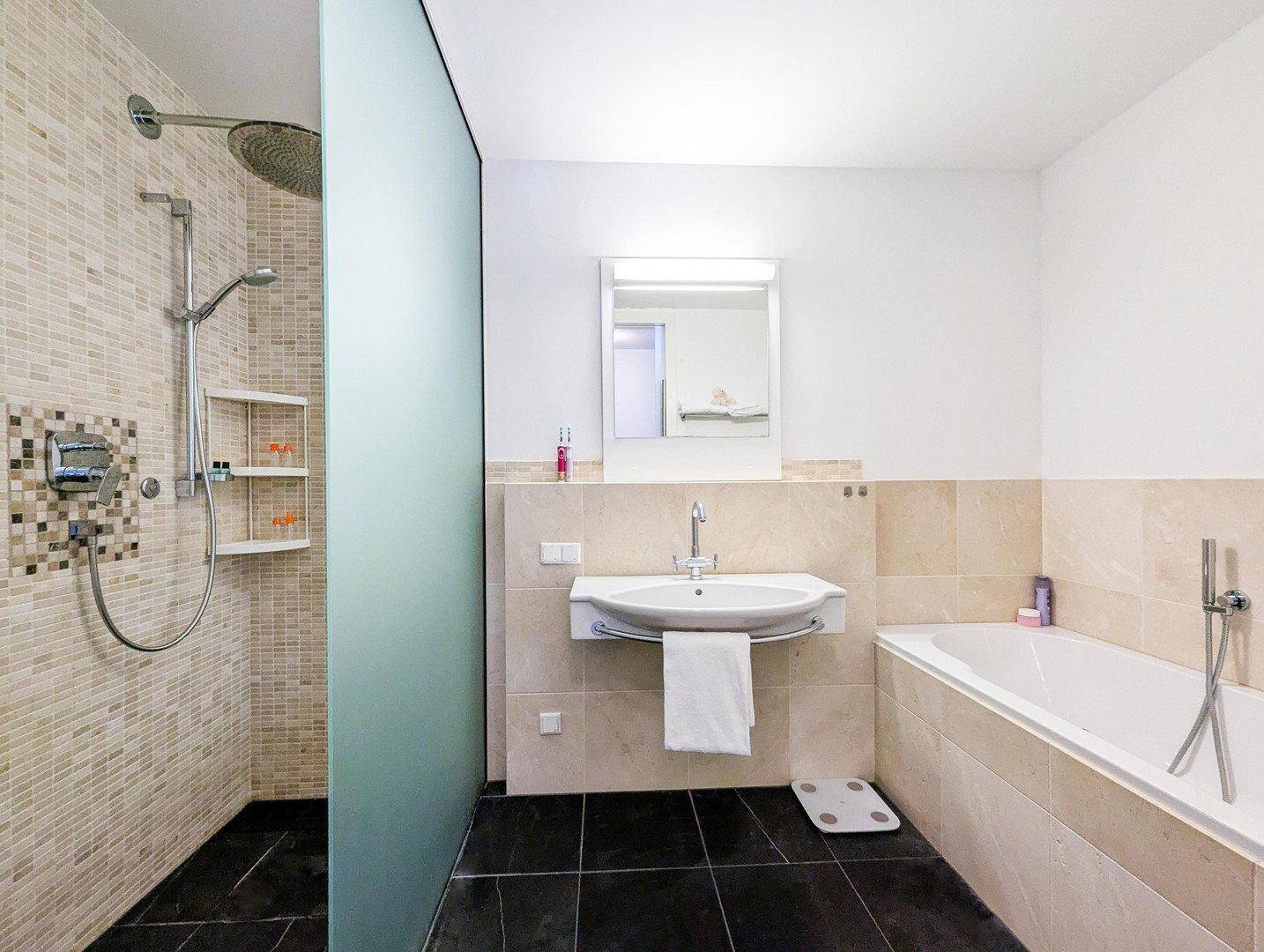 Modernes Badezimmer mit begehbarer Dusche, Badewanne und beigefarbenen Fliesen.