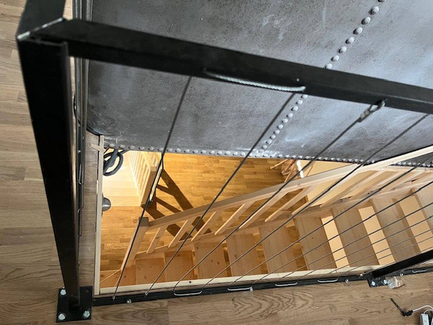 Blick von oben auf eine Holztreppe mit modernem Metallgeländer und Holzboden.