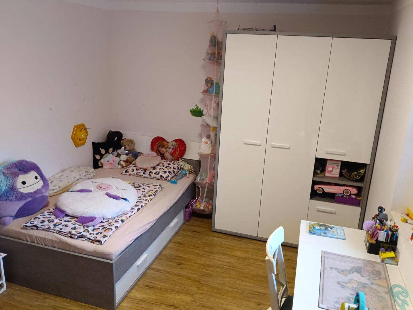 Gemütliches Kinderzimmer mit Bett, Kleiderschrank und Laminatboden.