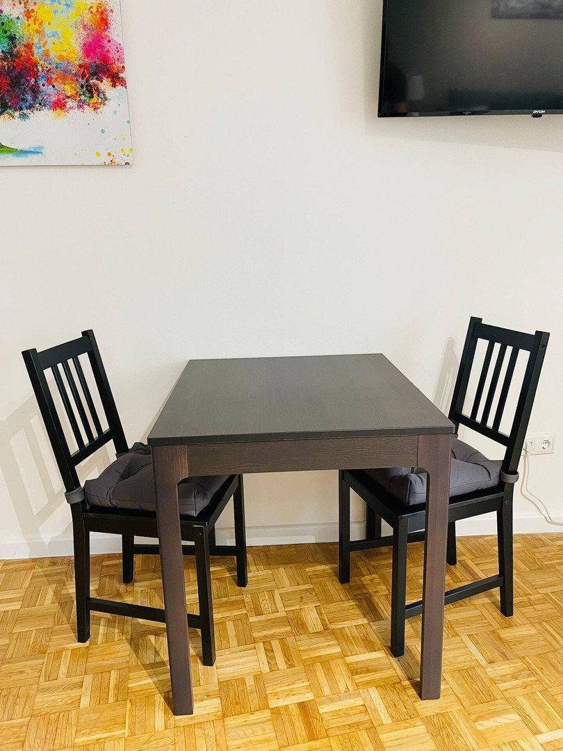 Kleiner Essbereich mit dunklem Holztisch und Stühlen, ideal für zwei Personen.