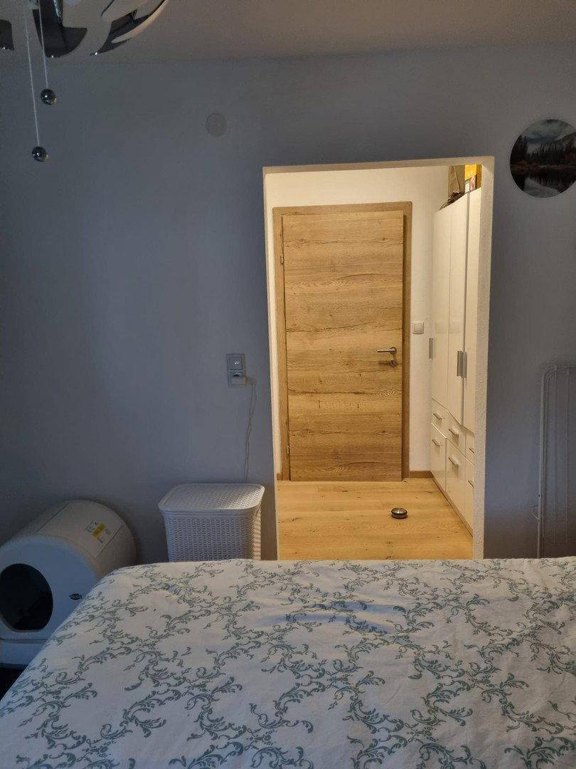 Schlafzimmer mit Holztür und Einbauschrank, ausgestattet mit einem gemusterten Bett.
