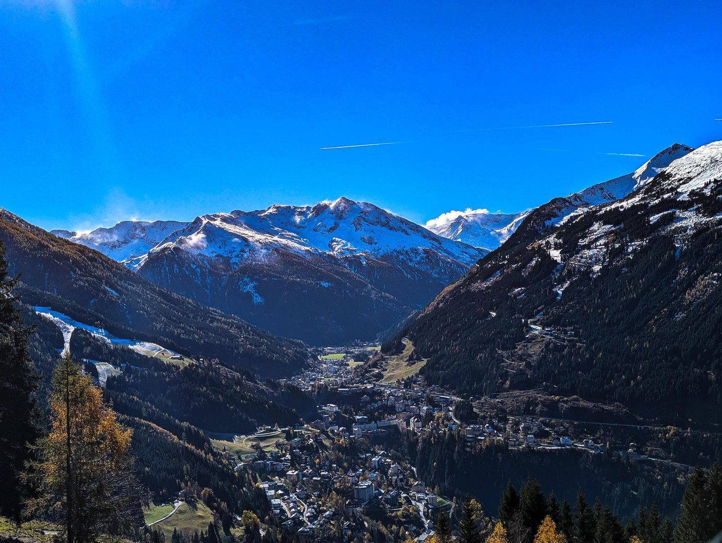 Atemberaubender Weitblick über ein tiefes Tal mit einem Dorf, umgeben von majestätischen, schneebedeckten Bergen.