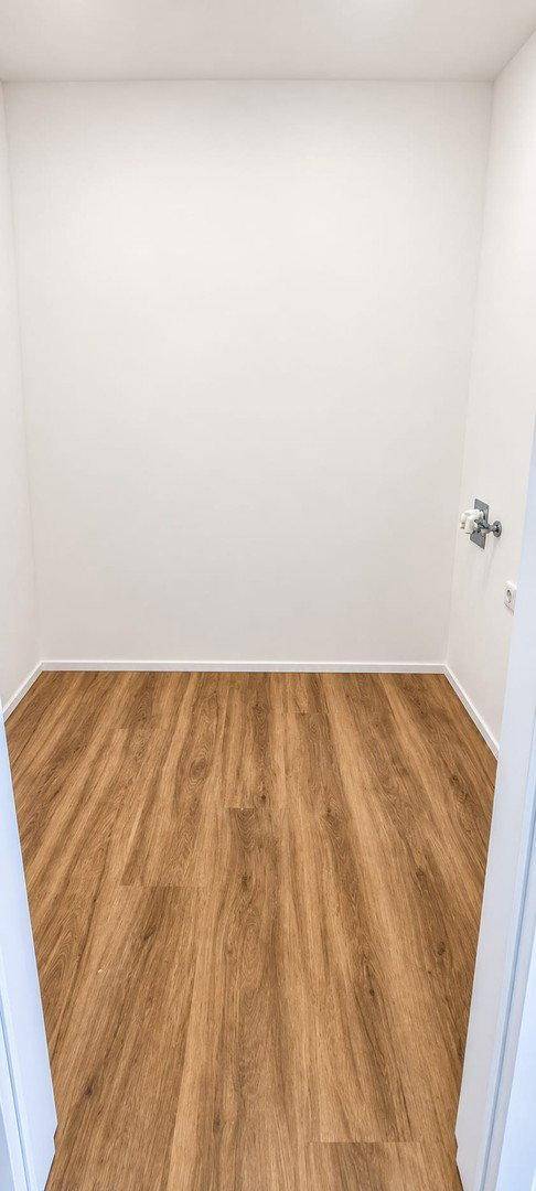 Praktischer Abstellraum mit Laminatboden und Anschlüssen, ideal für Waschmaschine oder Lagerung.