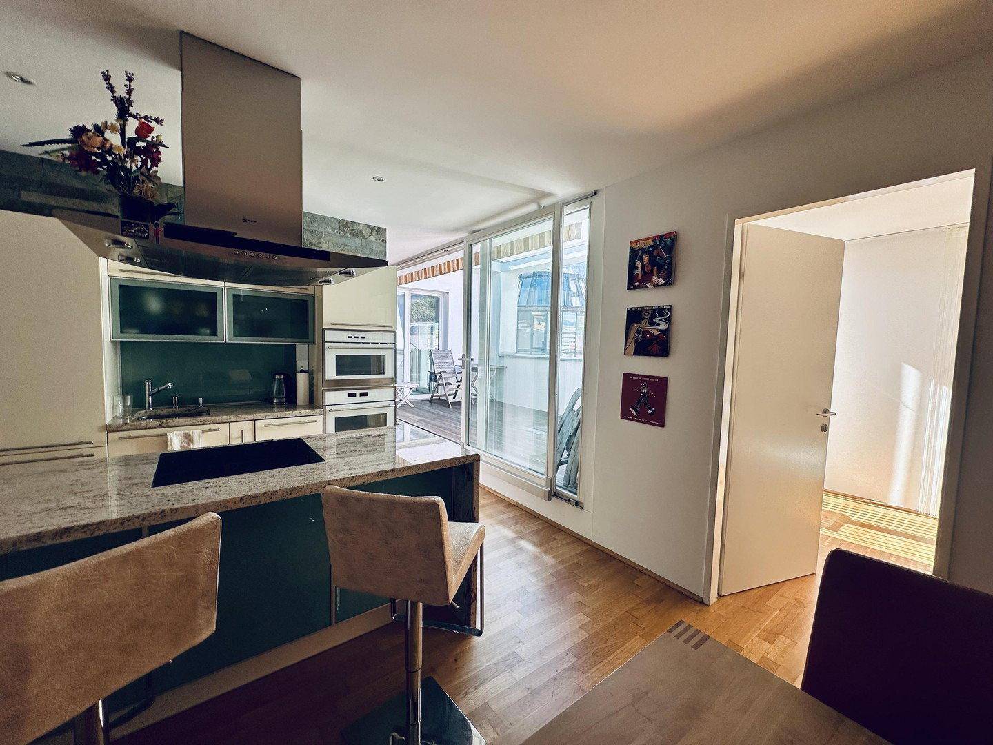 Offene Küche mit Kochinsel, Granitarbeitsplatte und Zugang zur sonnigen Terrasse.