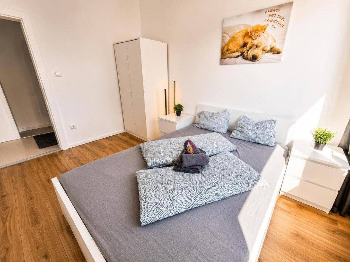 Helles Schlafzimmer mit Doppelbett, Nachttischen und einem weißen Kleiderschrank.