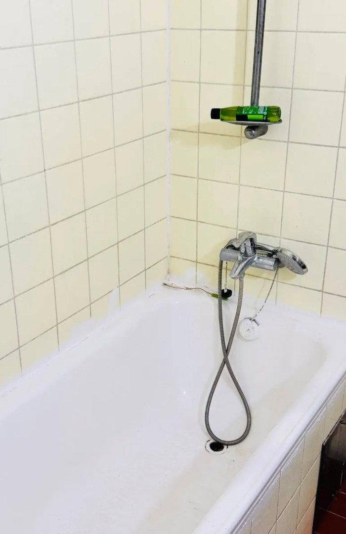 Badezimmer mit einer Badewanne und hellbeigen Fliesen an den Wänden.