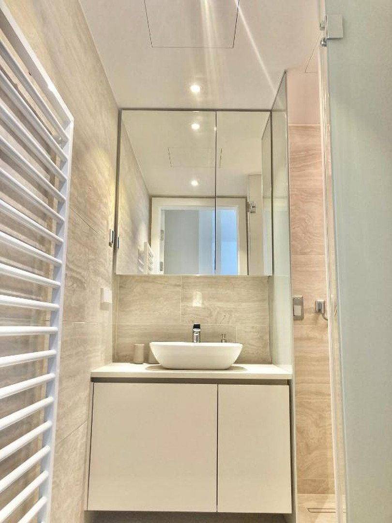 Helles Badezimmer mit modernem Waschtisch, Aufsatzwaschbecken und großem Spiegelschrank.